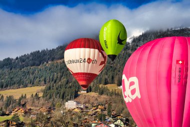 Chateau-d 'Oex, İsviçre - 1 Şubat 2025: İsviçre Alpleri' ndeki yıllık festivalde sıcak hava balonları yükseliyor