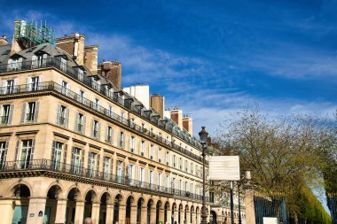 Mavi gökyüzünün altında kemerleri ve balkonları olan geleneksel Paris binaları