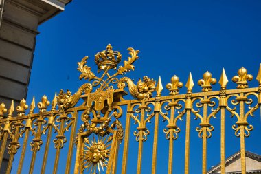 Versailles Sarayı 'nın süslü altın kapısı, parlak mavi gökyüzünün altında parlıyor.