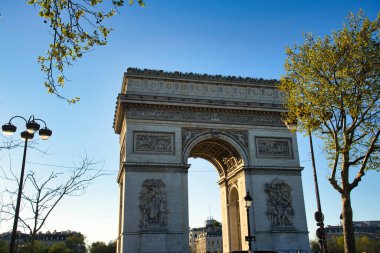 08.04.25.Paris, Fransa. Paris 'teki Zafer Takı' nın arkasında, ağaçların arasından görülebilen güzel altın gün batımı..