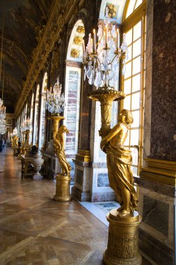08.04.25.Paris, Fransa Versailles Sarayı 'nda kristal avize ve çiçek duvarlı bir oda.