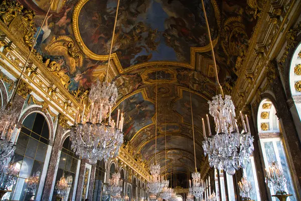 08.04.25.Paris, Fransa Versailles Sarayı 'nda kristal avize ve çiçek duvarlı bir oda.