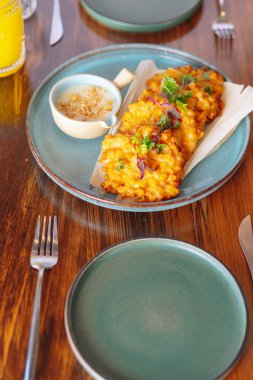 Masada soslu bir tabak kızarmış yemek var. Masa çatal, bıçak ve kaşıkla hazırlandı.