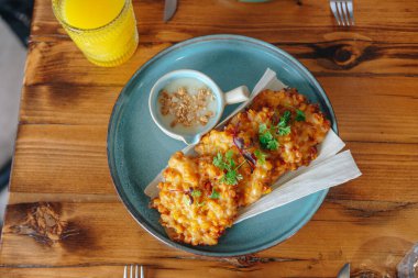 Bir tabak kızarmış yemek, mavi tabak ve beyaz peçete. Peçete katlanır ve yemeğin üstüne yerleştirilir.