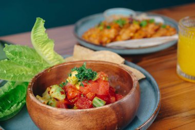 Üzerinde yeşil bir yaprak olan bir kase yiyecek. Kase ahşap bir masanın üzerinde.