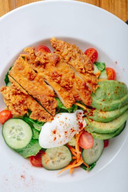 Tavuk, avokado ve sebzeli bir tabak yemek.