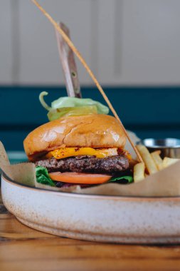 Hamburger, çörek ve bir parça marul. Tabakta patates kızartması da var.