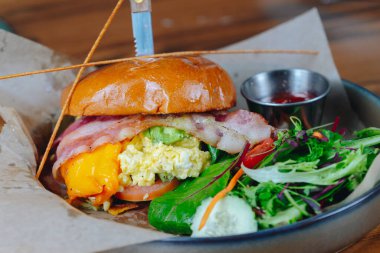 Salatalı pastırmalı yumurtalı sandviç. Sandviç tabağın üzerinde, üzerinde bıçak var.