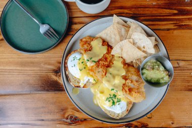 Yanında cips ve guacamole olan bir tabak yemek. Tabak ahşap bir masanın üzerinde.
