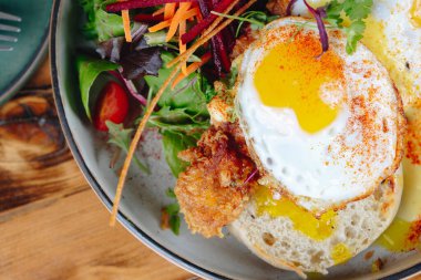 Bir tabak yemek, sahanda yumurta ve yanında sebze. Tabak ahşap bir masanın üzerinde.
