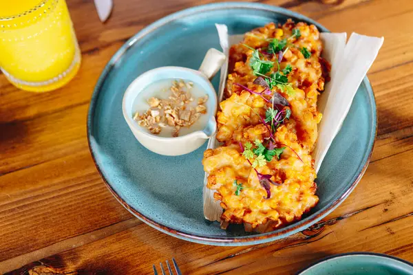 Ahşap bir masada soslu bir tabak kızarmış yemek.