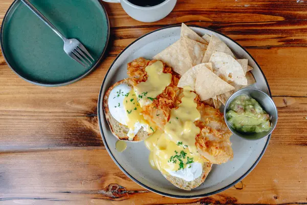Yanında cips ve guacamole olan bir tabak yemek. Tabak ahşap bir masanın üzerinde.