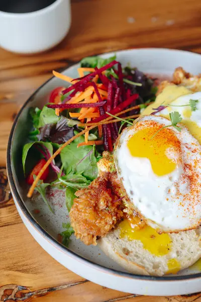 Bir tabak yemek, sahanda yumurta ve yanında sebze. Tabak ahşap bir masanın üzerinde.