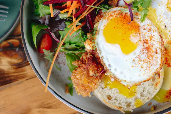 Bir tabak yemek, sahanda yumurta ve yanında sebze. Tabak ahşap bir masanın üzerinde.