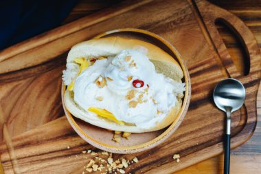 Fındıklı bir kase dondurma ve tahta kesme tahtasının üzerinde bir kaşık.