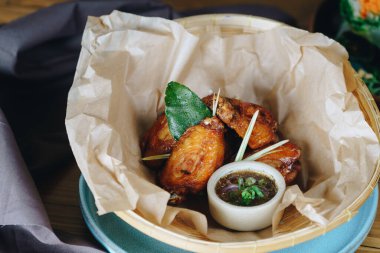 Soslu ve otlu bir tabak kızarmış tavuk. Tavuk bir sepette servis edilir ve sos küçük bir kasede. Sahne sıradan ve davetkar.