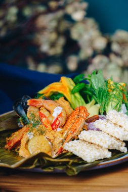 Bir tabak karides, sebze ve kraker. Tabak ahşap bir masanın üzerinde.