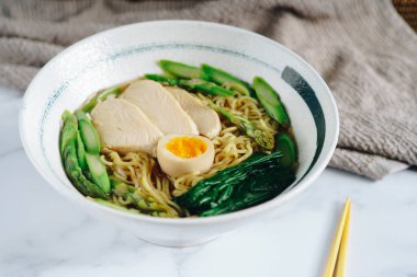 Tavuk, kuşkonmaz ve yumurtalı bir kase ramen.