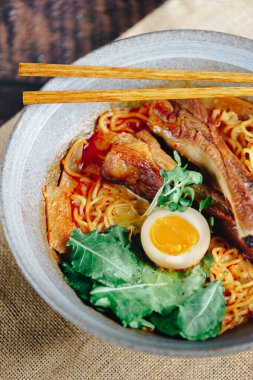 Üstünde bir parça yumurta olan bir kase ramen. Kase erişte ve etle dolu.