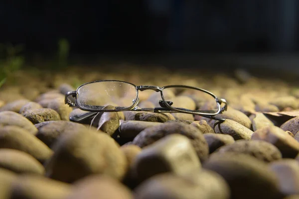 old glasses with black optical frames made of iron are among the rocks
