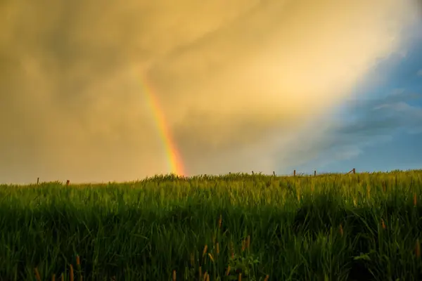 Atmospheric landscape with rainbow, clouds and blue sky