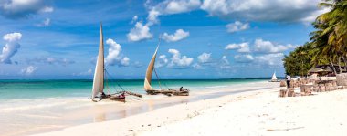 Geleneksel olarak Zanzibar sahilinde balık avlıyoruz. Turkuaz okyanusta tekneler ve mavi gökyüzü, manzara.