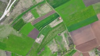 Birçok arazi ve çayır üzerinde hava aracı videosu, yavaşça yerel yola hareket ederek, köyün yakınındaki 4K 60fps köyüne gidiyor.