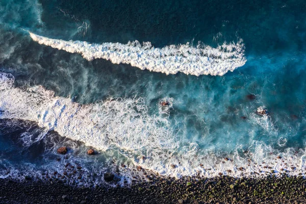 Aerial top view at the waves on the blakc volcainc beach in the
