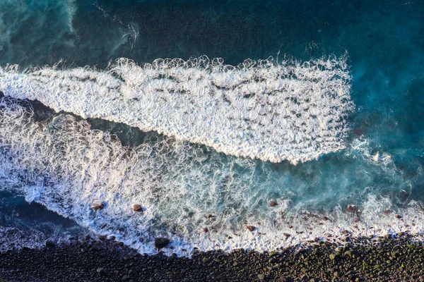 Aerial top view at the waves on the blakc volcainc beach in the