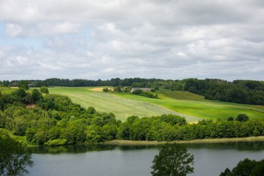 Kashubia 'da yaz: Polonya' nın Zawory kentinde Brodno Gölü yakınındaki yeşil tepeli güzel pastoral manzara