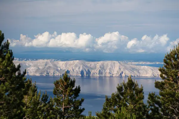 stock image View from above of the rocky cliffs of the island, illuminated by the light of the rising sun and shaded by occasional clouds.