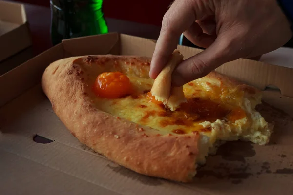 A man tries Ajarian style khachapuri - baked dough with raw egg