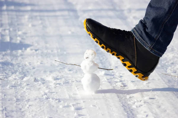 a little snowman being crushed by a big foot