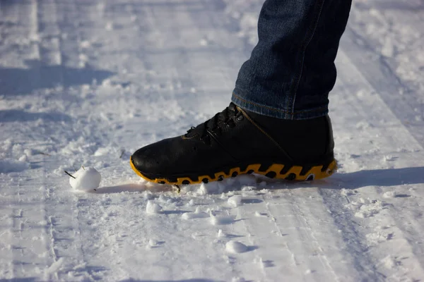 a little snowman being crushed by a big foot