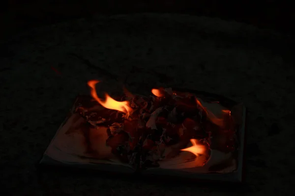 An open book lying on a concrete slab and burning