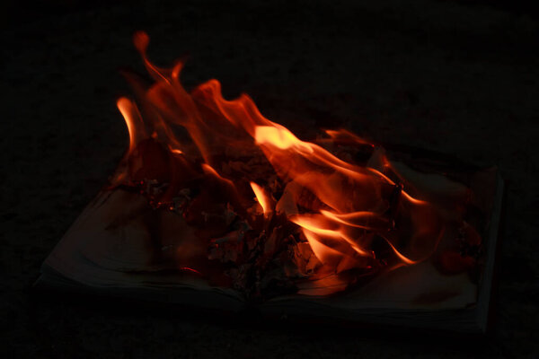 An open book lying on a concrete slab and burning