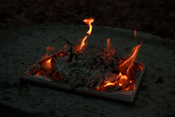 An open book lying on a concrete slab and burning