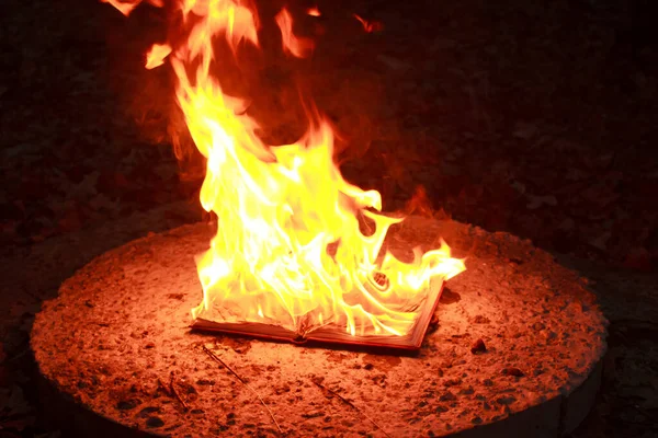 An open book lying on a concrete slab and burning