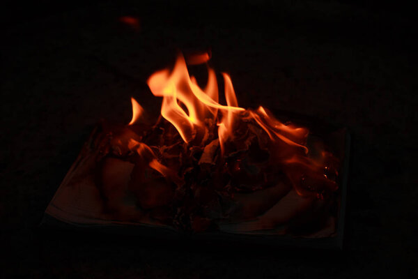 An open book lying on a concrete slab and burning
