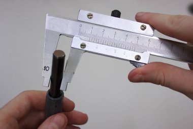 Measuring a metal shaft with two-handed calipers