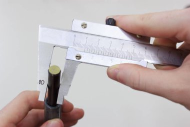 Measuring a metal shaft with two-handed calipers