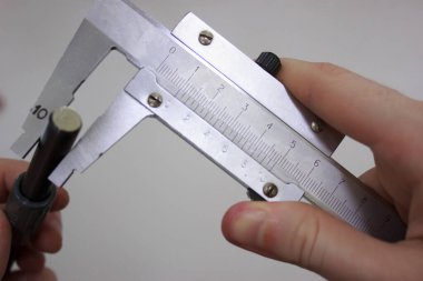 Measuring a metal shaft with two-handed calipers