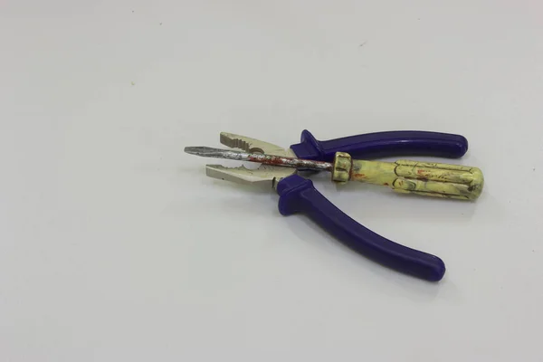 Pliers and screwdriver lying together on a gray background
