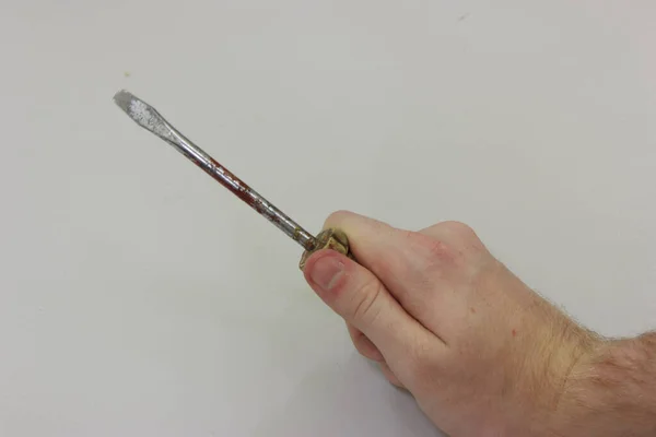 Minus screwdriver in a man's hand on a gray background