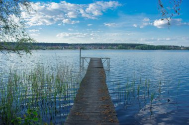 Pedestrian bridge to the pier with a bench in the middle of a large lake