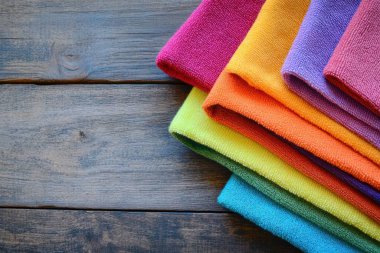 Colorful microfiber cloths arranged on wooden surface clipart