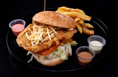 Crispy chicken burger on black background. Tomato, lettuce, chicken burger, sauces and fries. nice clipart