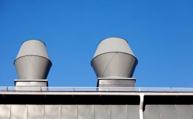 two chimneys in gray sheet metal against a blue sky