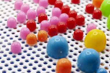 Beyaz delik deseninde farklı renklerde küçük plastik tıkaçlar