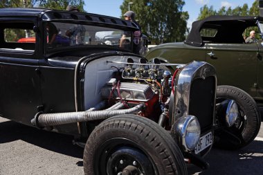 Açığa çıkmış motoru ve geleneksel özelleştirmesi olan tehditkar siyah bir hot rod..